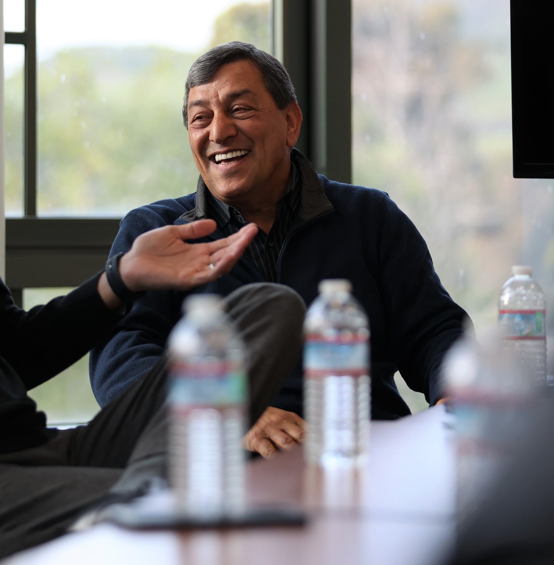 Professor Cyrus Ramezani laughs with colleagues at a conference table.