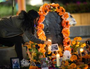 A student places a candle on an ofrenda.