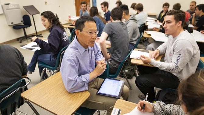 Mechanical engineering professor John Chen working with students during a lecture.