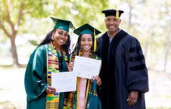 From left: Dionna Glover, Genesis Glover and Victor Glover, all wearing graduation regalia, smile for a family photo. Dionna and Genesis both hold their diplomas.