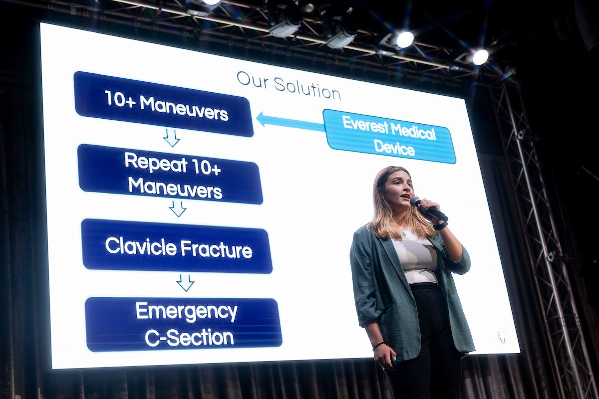 Everest Medical CEO Jenna Eissmann stands on a stage with a screen behind her.