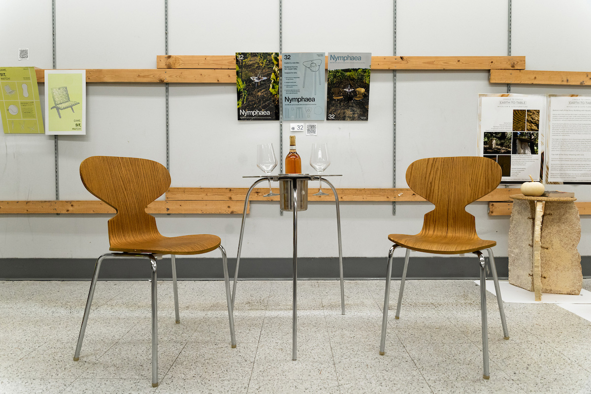 A steel table sits between two abstract wooden chairs.