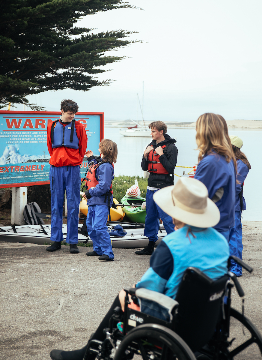 Luke Hansen, left, interacts with community members wearing life jackets in Morro Bay.