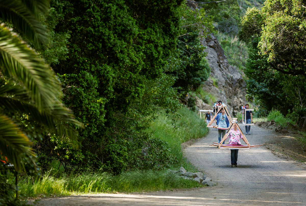 Students carry materials down a hiking path.