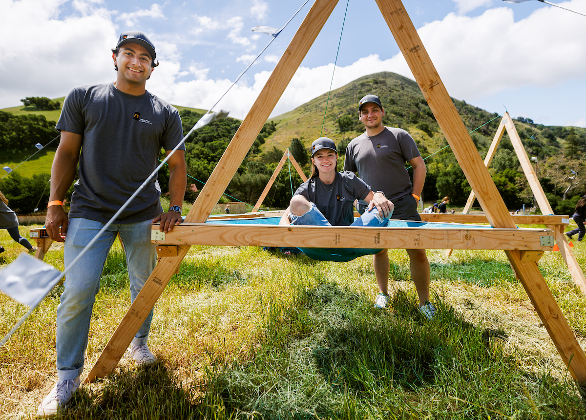 Three students pose with their wooden structure in Poly Canyon.
