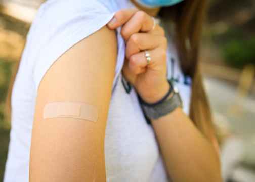 A person in short-sleeve shirt shows bandage after receiving vaccine