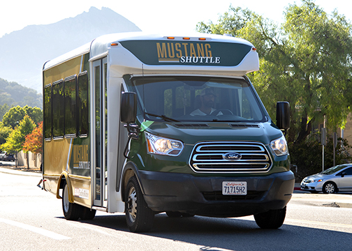 A Mustang Shuttle drive on campus perimeter road with Bishop Peak in the background