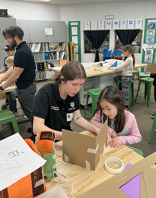 Two Cal Poly students are pictured assisting children with cardboard toolbox projects in an after-school Maker's Club at Santa Margarita Elementary School.