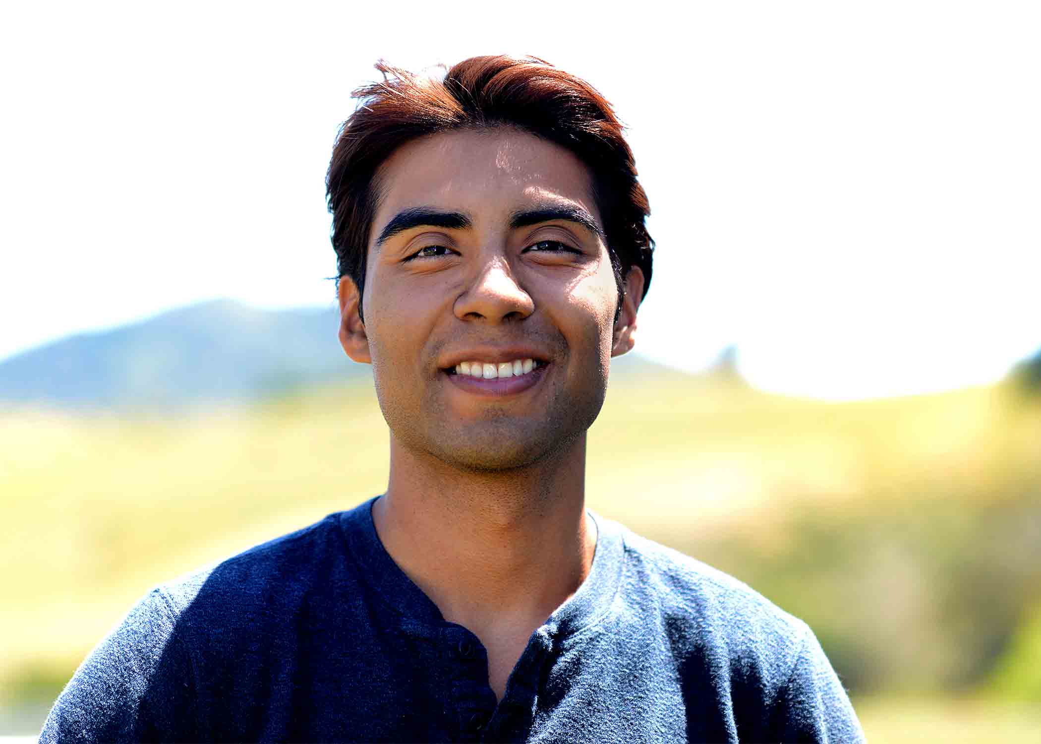 A portrait photo of Isaac Lopez, outside in the sun.