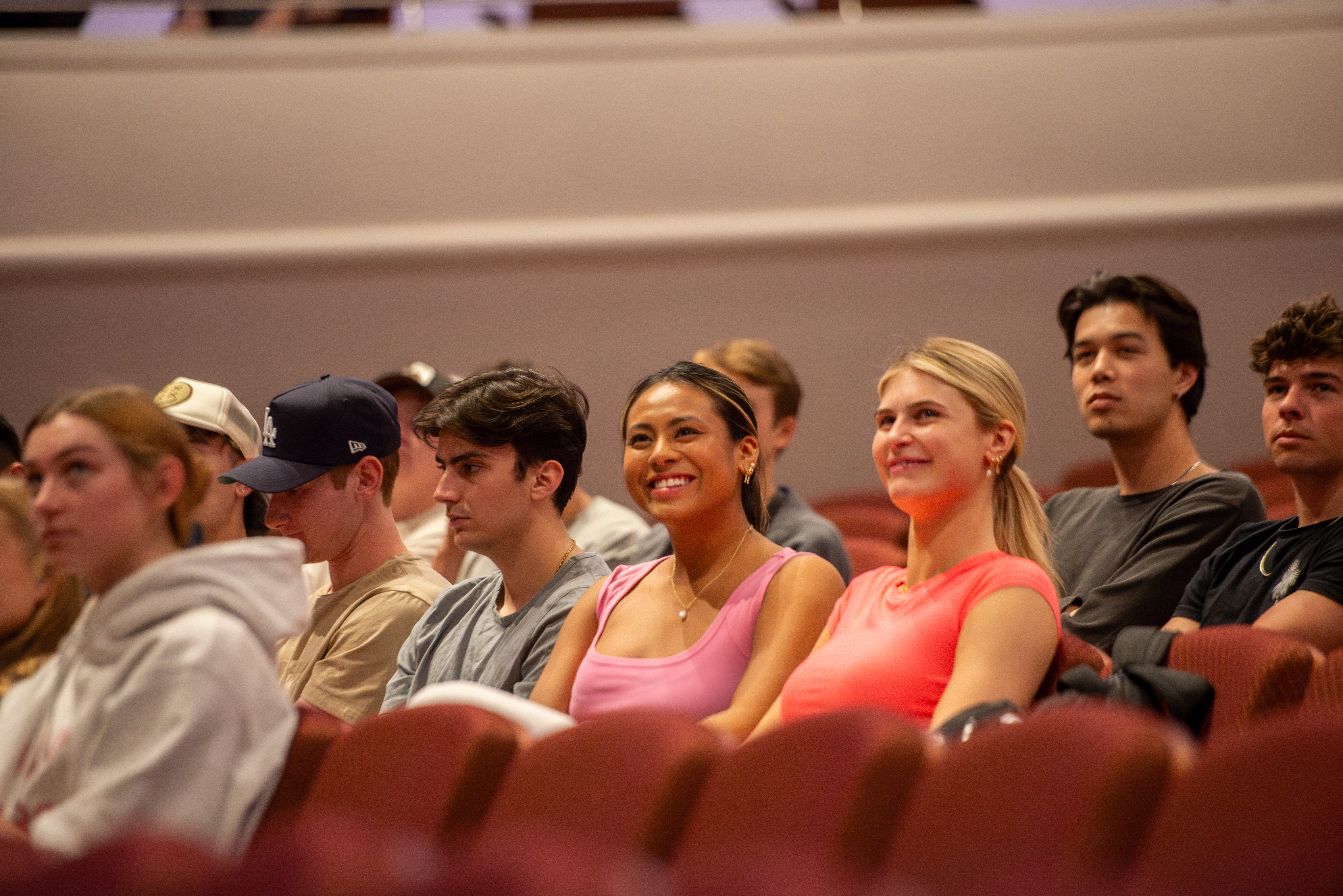 Students smile as they sit in an auditorium.