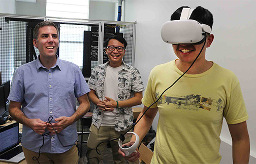 A faculty member and two students test out a 3D video produced with the help of artificial intelligenc