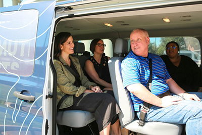 employees shown in the back of a van with the sliding door open