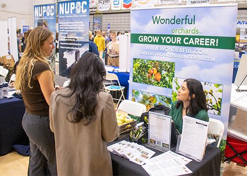 Two female students talk to a company representative during a Cal Poly career fair event