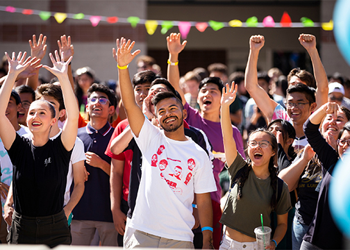 A group of male and female students raise hands during a CultreFest event on campus