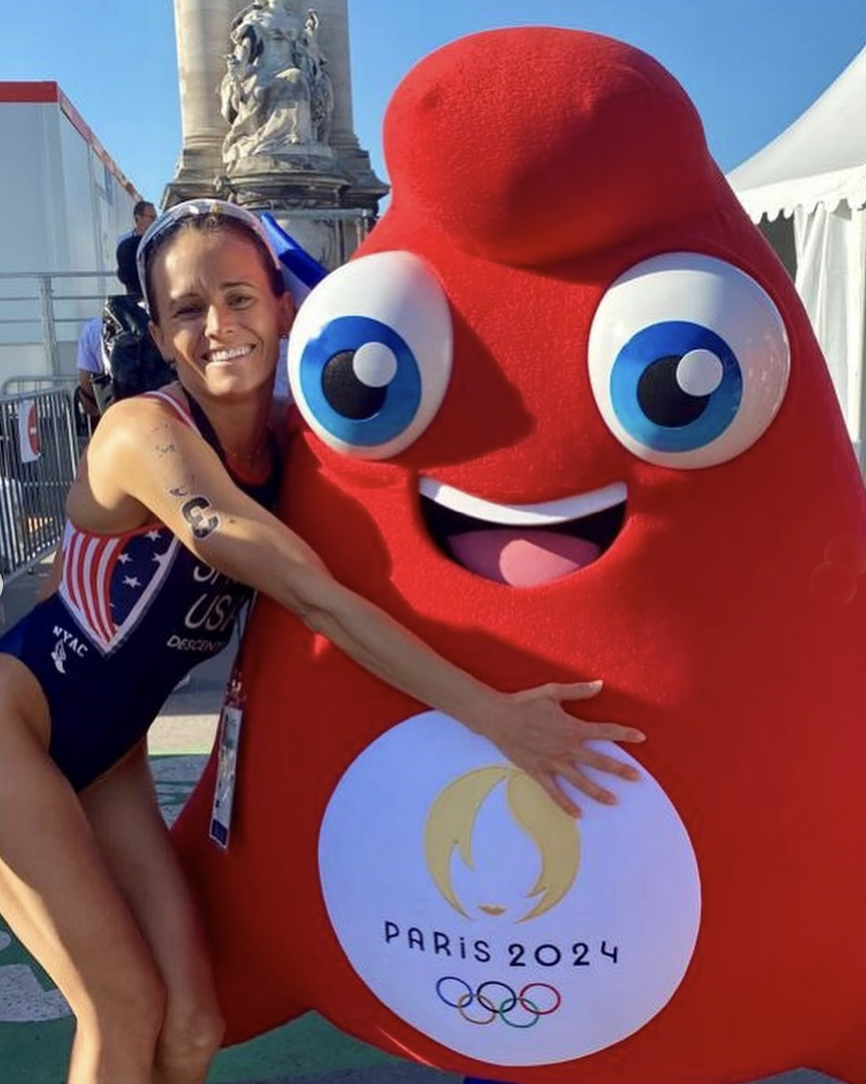 Cal Poly alumna Taylor Spivey hugs the Olympic Phryge mascot that takes the shape and form of a Phrygian cap