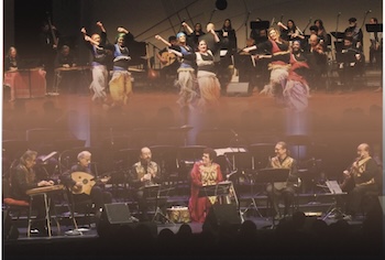 Performers dance and play instruments on stage.