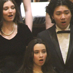 Three student choir singers perform dressed in black