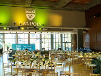 Chumash Auditorium decorated with gold chairs, uplighting and flowers on tables. 