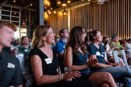 Audience smiles and claps hands watching presentation.