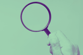 Photo of hand holding magnifying glass on green background.