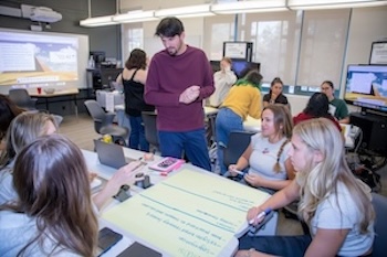 Students and faculty work on a group project in a classroom. 