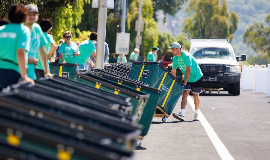 Faculty and staff help move rolling bins for new student move in.