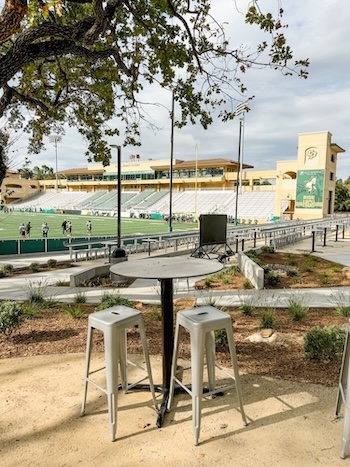 Bistro table with barstools under a tree with the view of Spanos Stadium in the background.