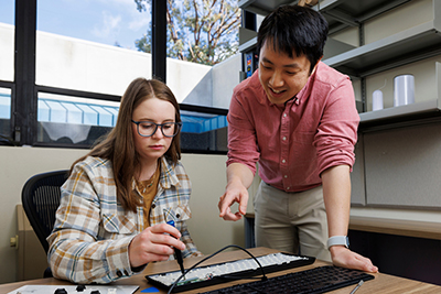 Two people work on repairing a keyboard in an office setting