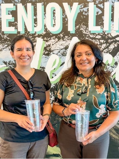 Two employees hold re-usable Cal Poly branded tumblers.