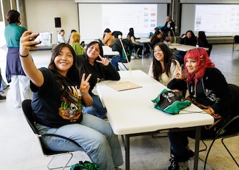 Students at a table pose for a selfie.