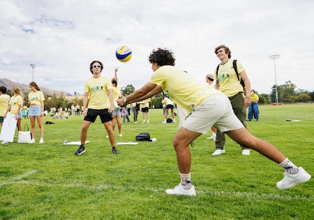 Students play volleyball on grass field during Week of Welcome.