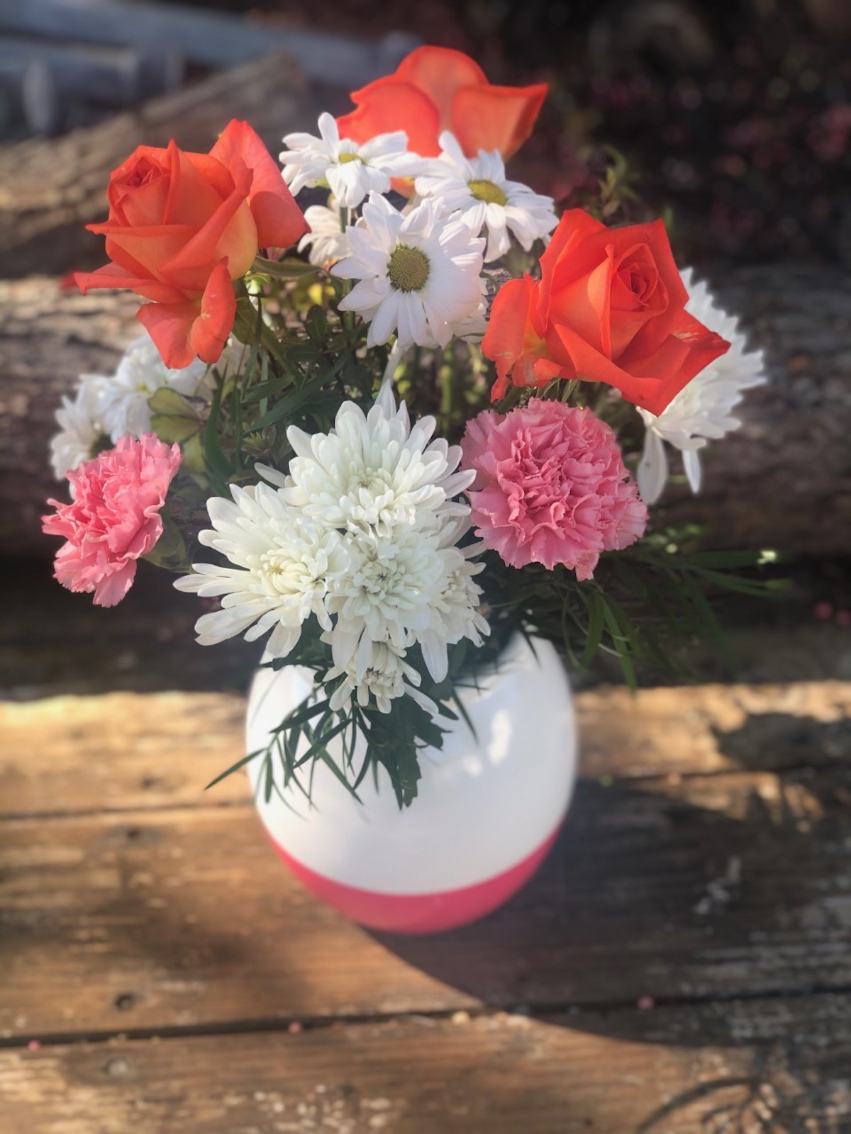 A bouquet containing orange roses and white daisies arranged by the Poly Plant Shop.