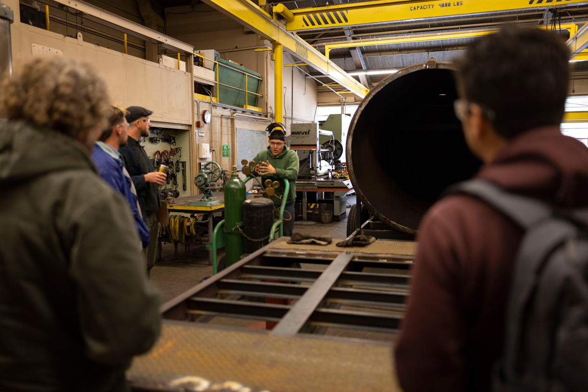 Students gather around compost spreading equipment in a lab.