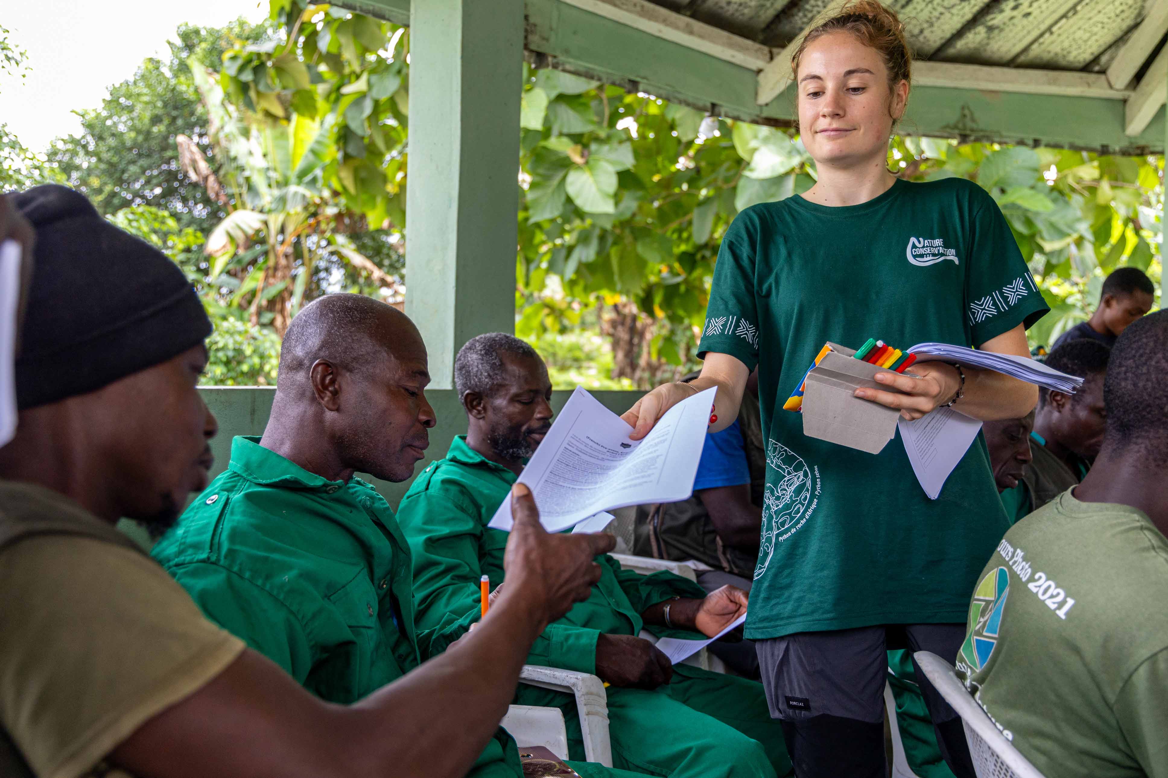 A volunteer in a green shirt hands out surveys to volunteers.