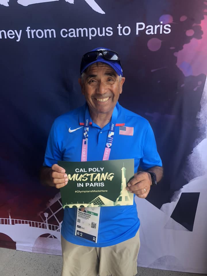 Manny Bautista poses with a sign that reads "Cal Poly Mustang in Paris"