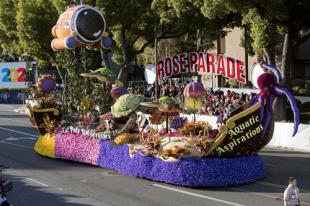 Brightly-colored float decorated with flowers, depicting marine animals and a submarine, displaying the title "Aquatic Aspirations"