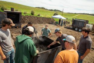 Students in a BRAES class work with a biochar kiln while doing research on climate smart agriculture.