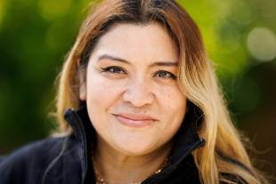 A woman in a black sweater smiles in a portrait.