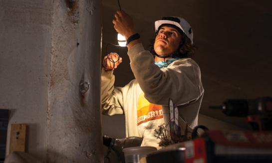 A student installs lighting in a home in the Navajo nation