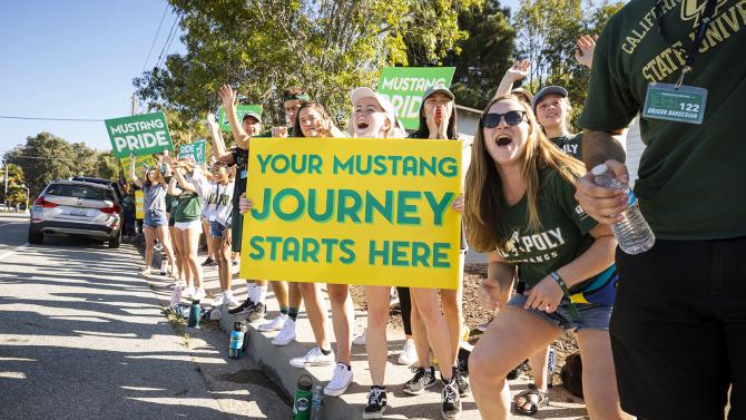 Group of students holding signs to welcome new students to campus