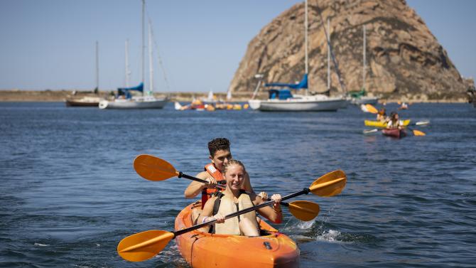 2 students in a kayak with morro rock in the background