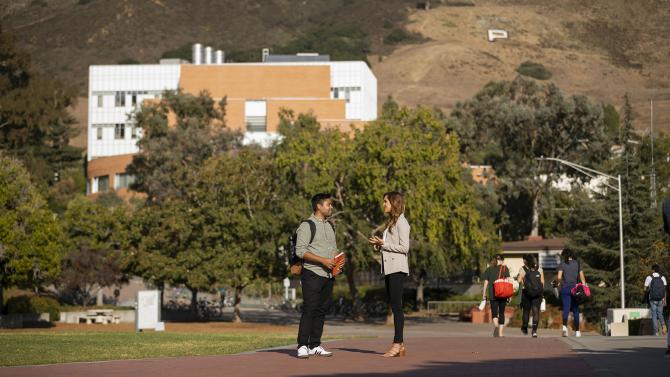 Two students have a conversation on Dexter Lawn