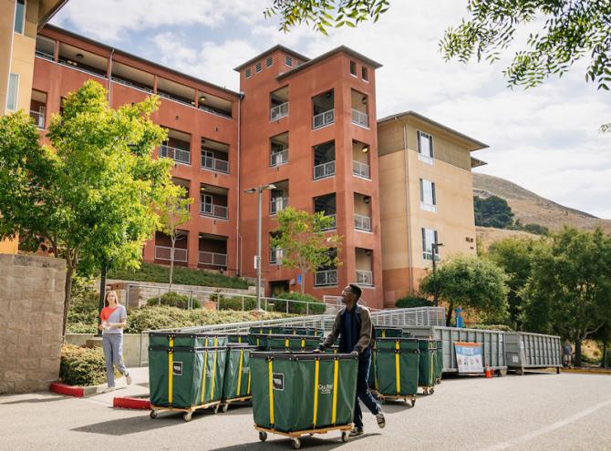 A student pushes a trolley of belongs at move in. 