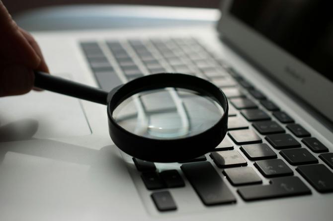 A magnifying glass sits on top of a computer.