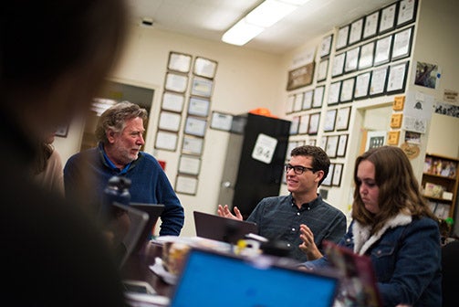 Mustang News editor in chief Austin Linthicum sits with two other people during a Mustang News meeting in 2019