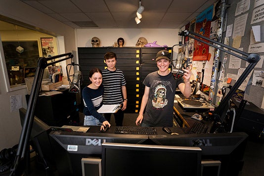 Three KCPR DJs laugh at the radio station in February 2020.