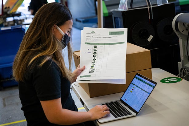 Kinsey Mangan sorts finished signs into boxes for delivery as she and other student employees print signage to be used in buildings on campus during the  coronavirus