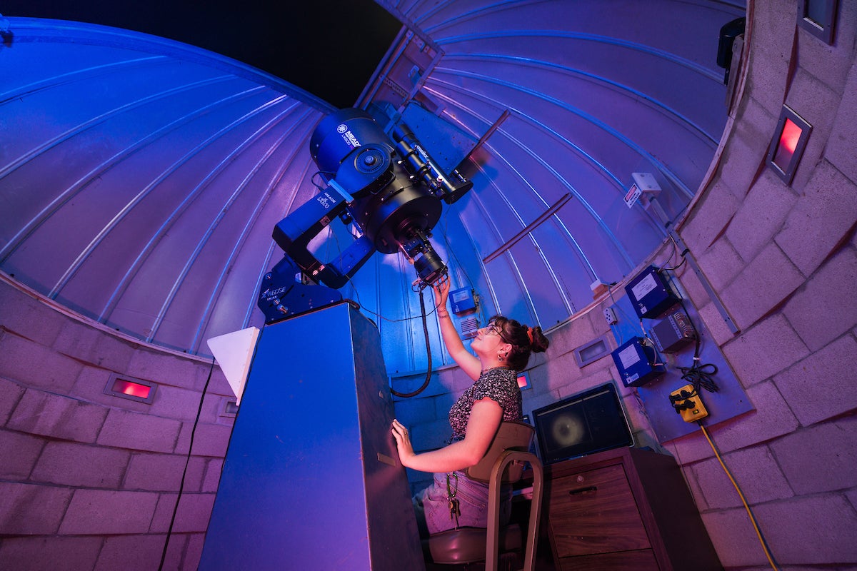 A woman looks through a telescope at the observatory on Cal Poly's campus.