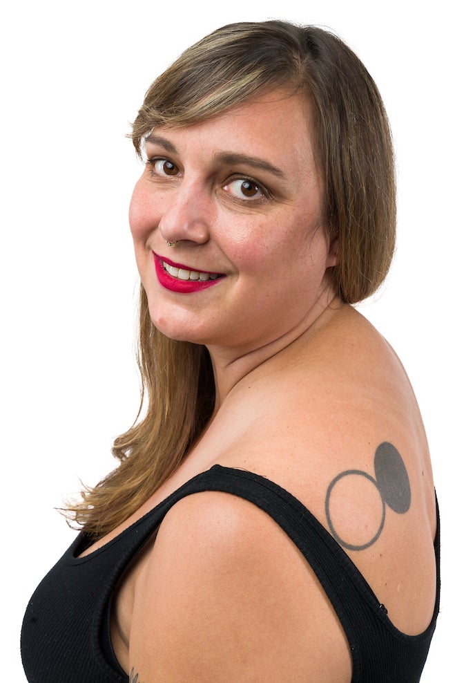 A woman smiles over her shoulder as she shows a tattoo of connected black and white circles