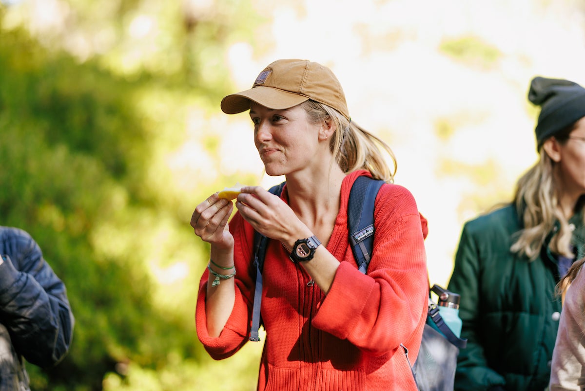 A female student in a red shirt holds a lemon wedge and looks pensive as she considers the flavor during a taste test party for class.